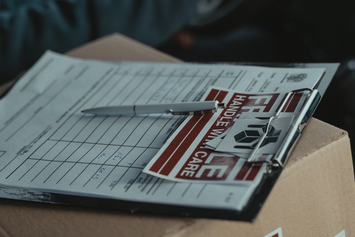 Un clipboard avec des papiers de livraison et un autocollant 'À manipuler avec