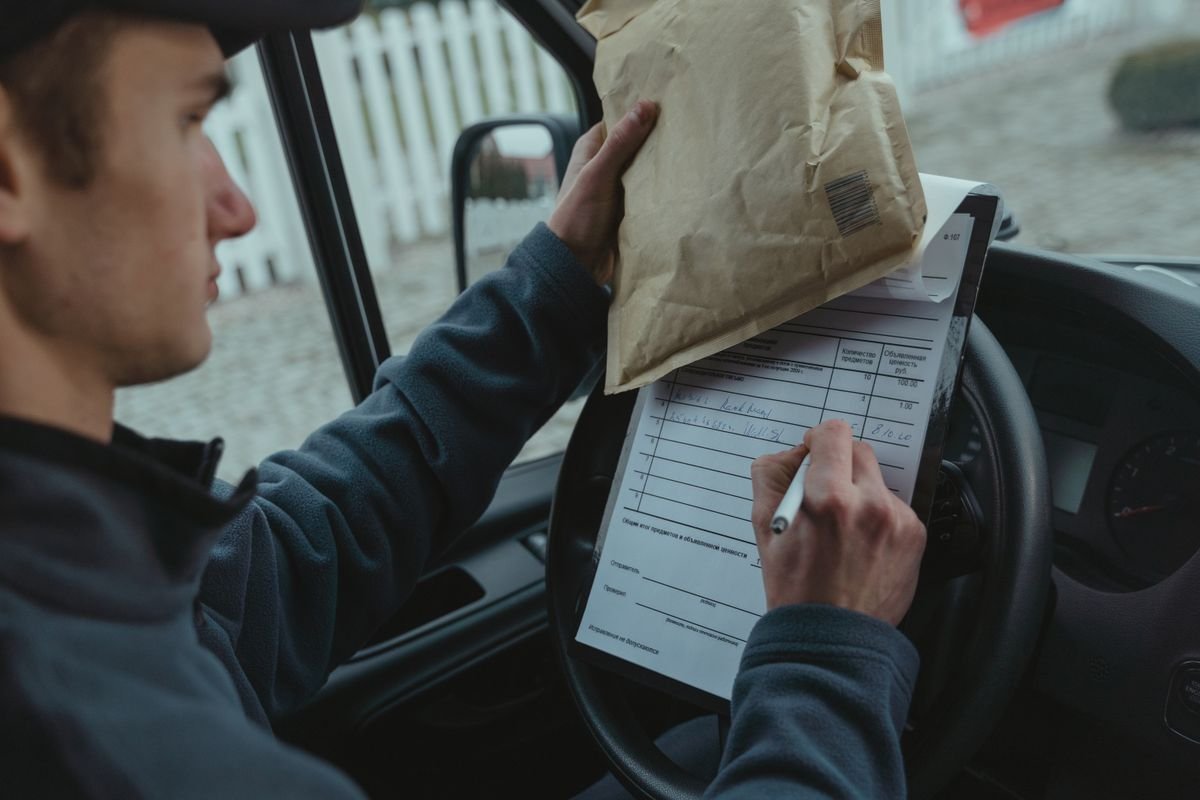 Un livreur signe des documents de livraison à l'intérieur d'un fourgon tout en