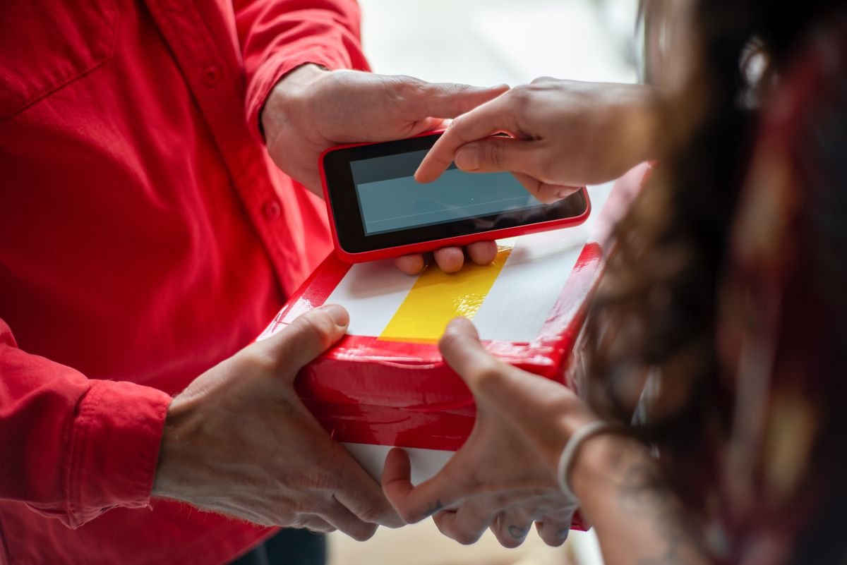 Mains échangeant un colis avec une signature électronique pour une livraison