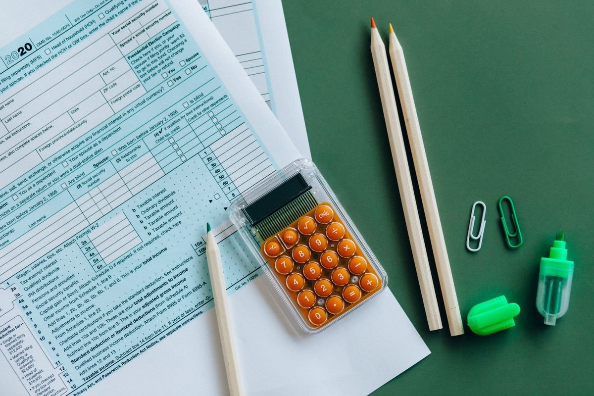 Vue de dessus de formulaires fiscaux, calculatrice, crayons et agrafes sur une