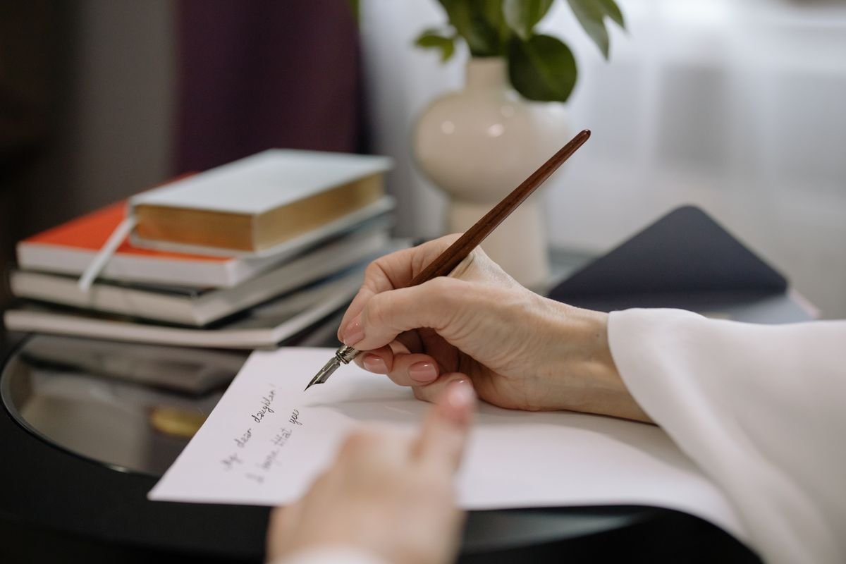 Médiateur de la consommation : l’obligation oubliée Gros plan sur une personne écrivant avec un stylo plume sur du papier, des