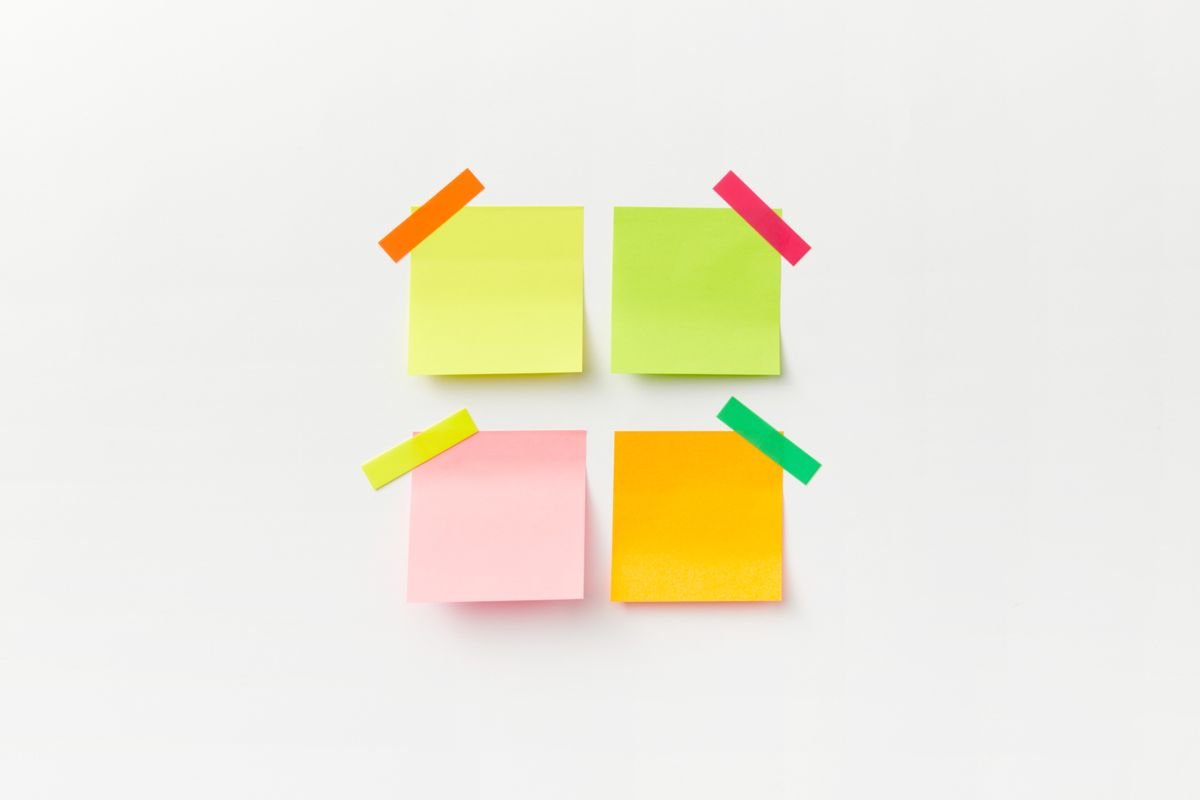 Quatre notes autocollantes colorées sur un fond blanc avec un ruban vif