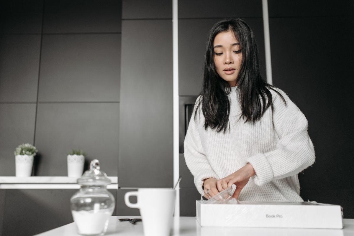 Jeune femme ouvrant une boîte dans une cuisine contemporaine, entourée de décor