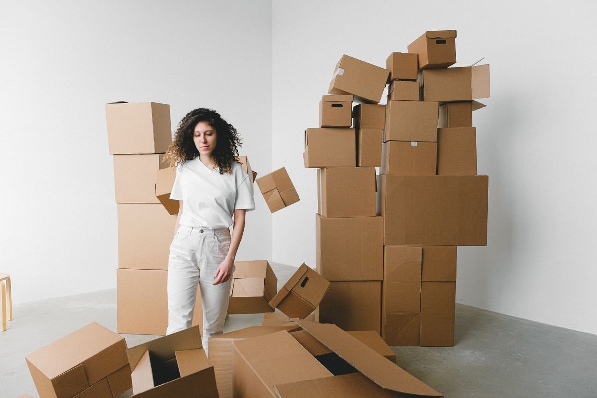 Frais de port : le paramétrage qui protège votre marge Une jeune femme se tient à l'intérieur, entourée de boîtes en carton empilées