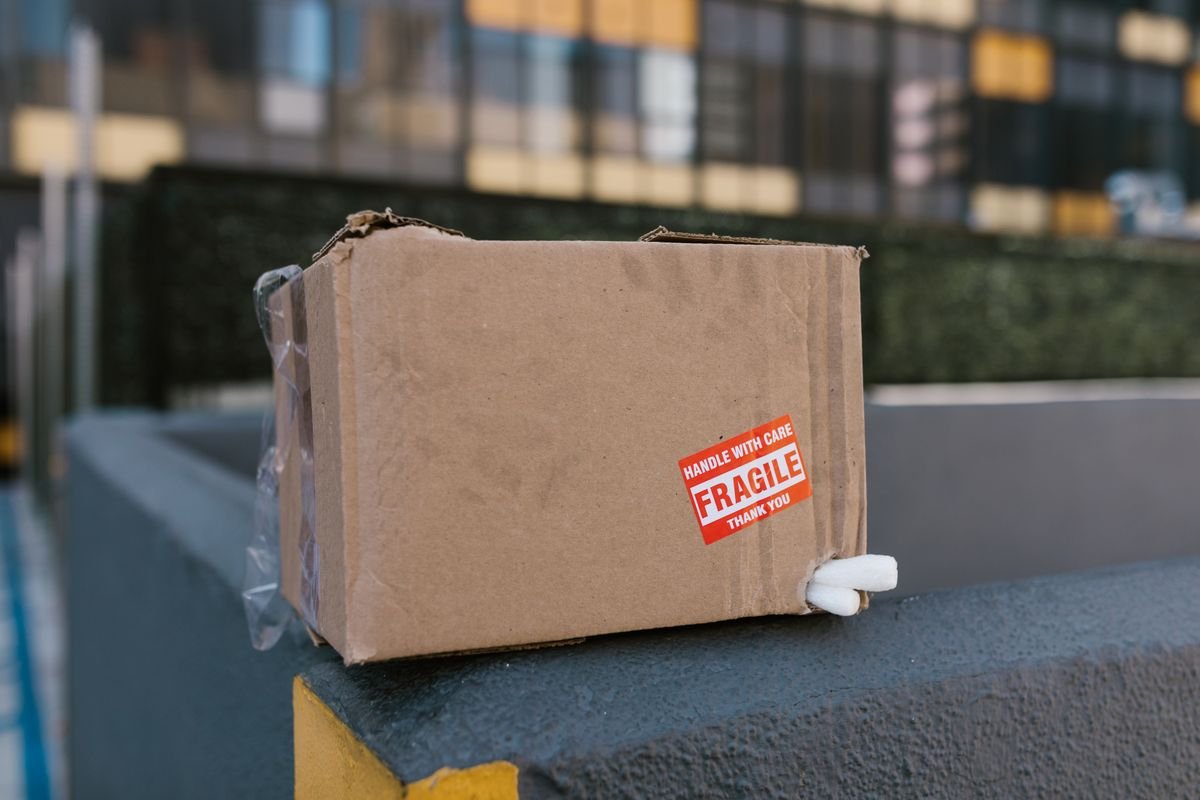 Gros plan sur une boîte en carton fragile sur un rebord en béton dans un