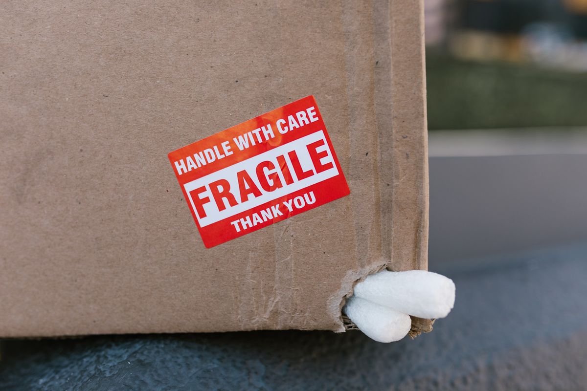 Gros plan sur une boîte en carton avec un autocollant 'fragile' et des cales en