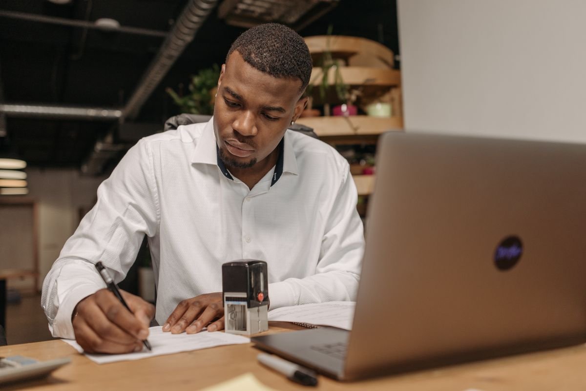 Un jeune homme en chemise blanche travaille avec assiduité à son bureau avec un