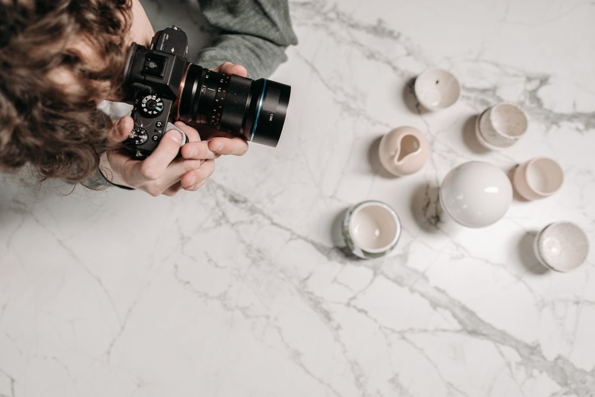 Homme photographiant des tasses en céramique sur une surface en marbre vue de