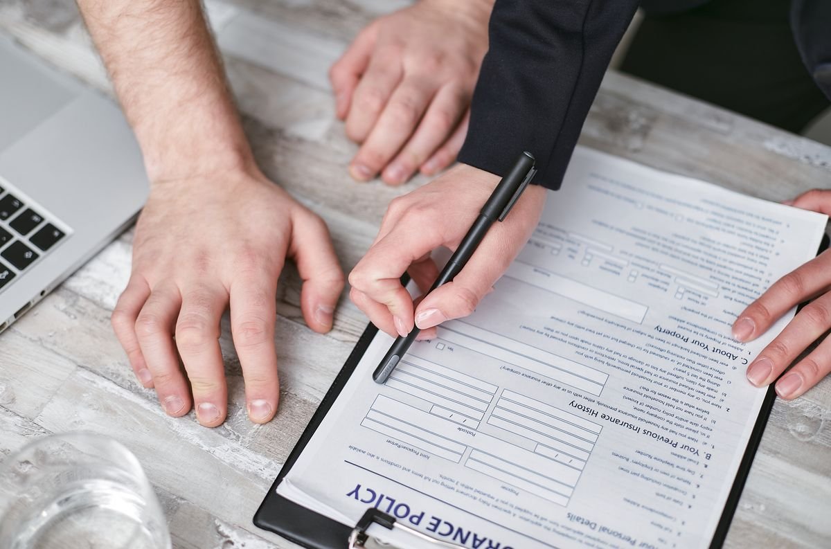 Image en gros plan de deux personnes signant un document de police d'assurance