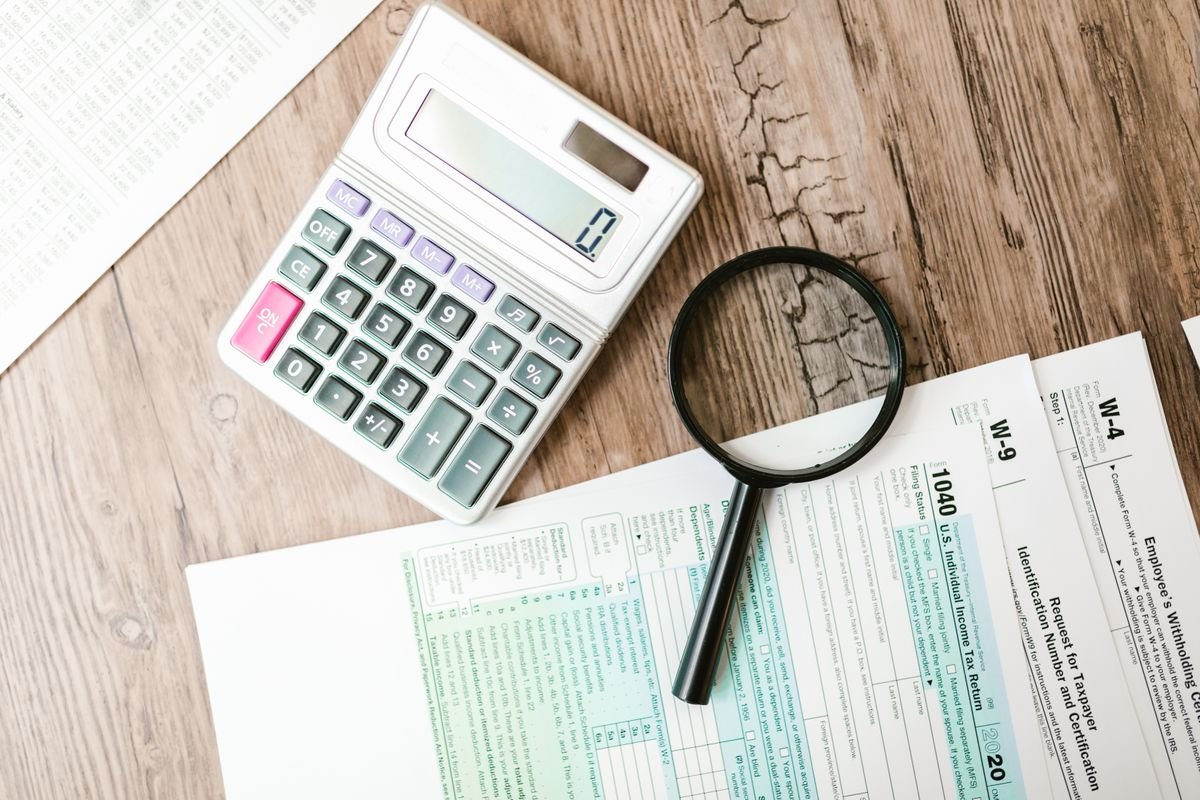 Des formulaires fiscaux disposés avec une calculatrice et une loupe sur une