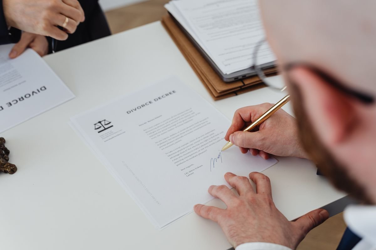 Gros plan d'une personne signant un décret de divorce sur un bureau