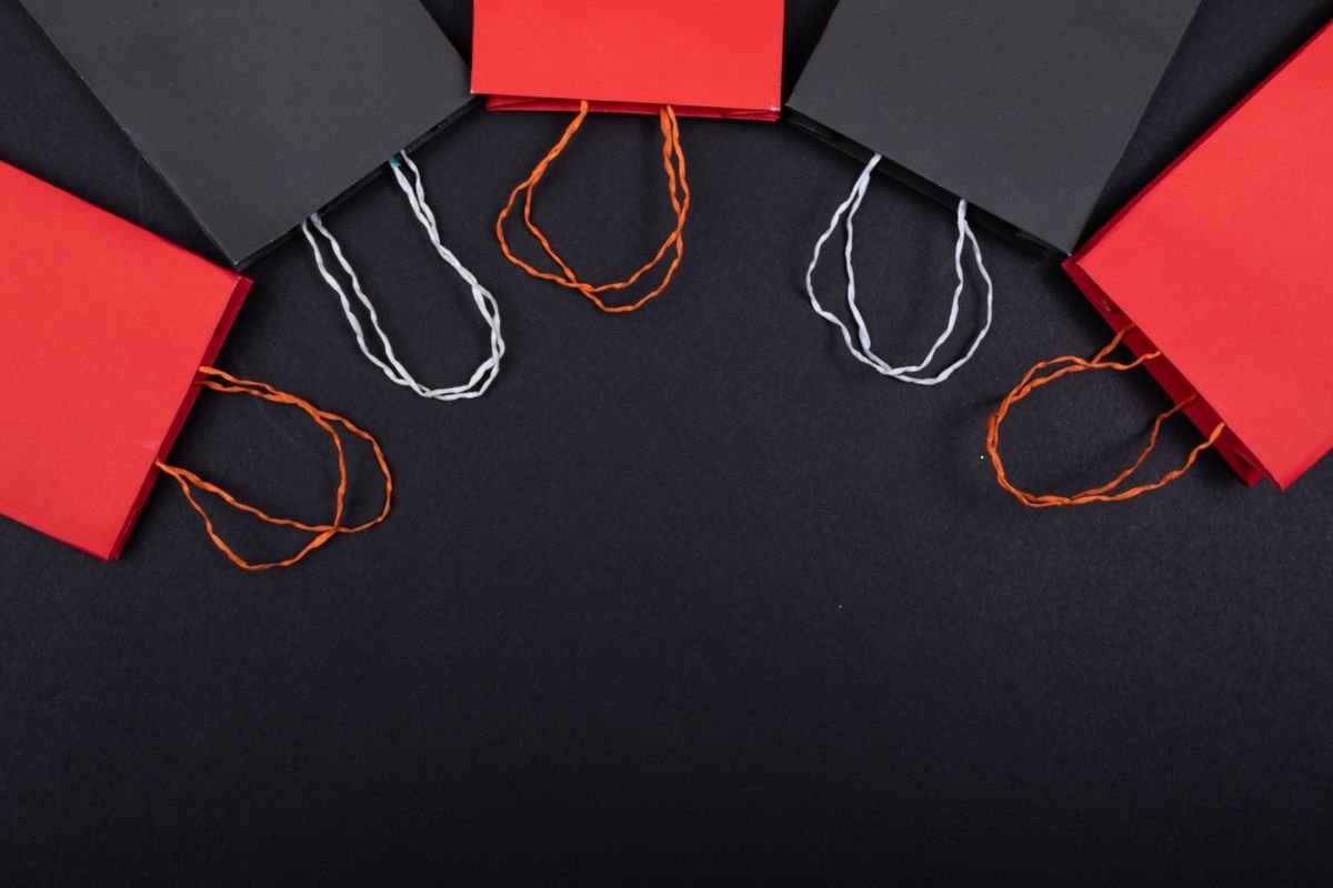 Mise à plat de sacs en papier rouges et noirs sur un fond noir avec espace de