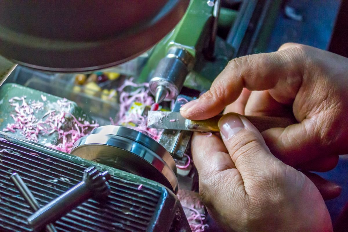 Des mains opèrent minutieusement une machine à tour
