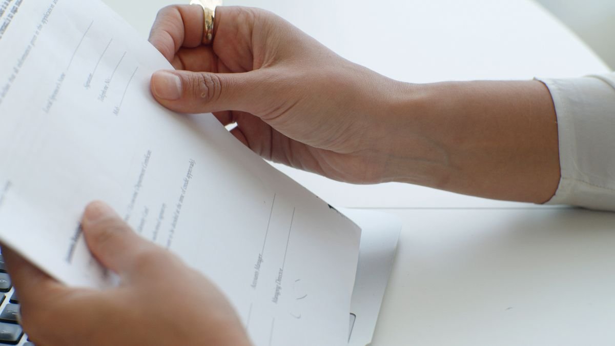 Vue rapprochée de mains tenant un document au-dessus d'un clavier dans un bureau