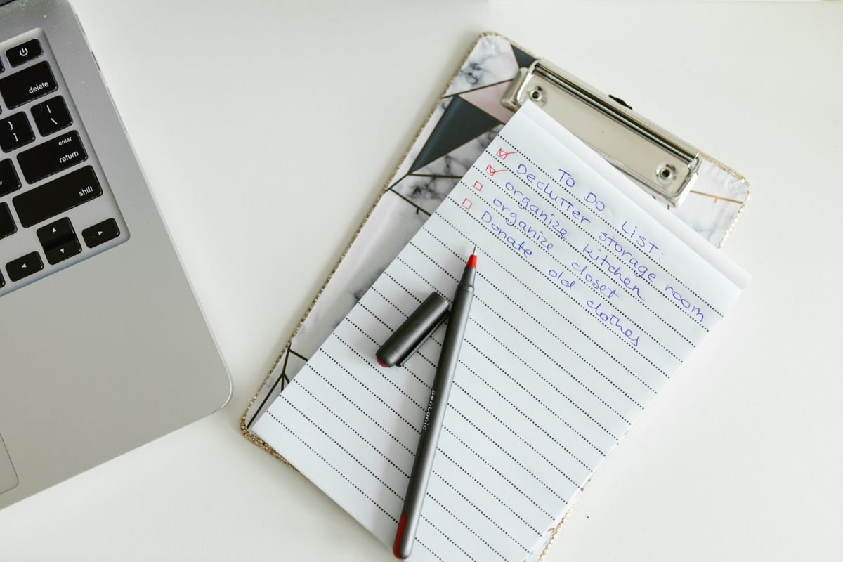 Une liste de tâches soigneusement organisée sur un carnet à clip à côté d'un