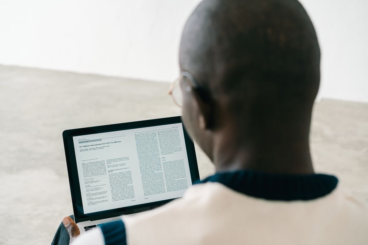 GEO : être cité par ChatGPT, Perplexity et les moteurs de réponse Homme chauve lisant un document sur l'écran d'un ordinateur portable dans un