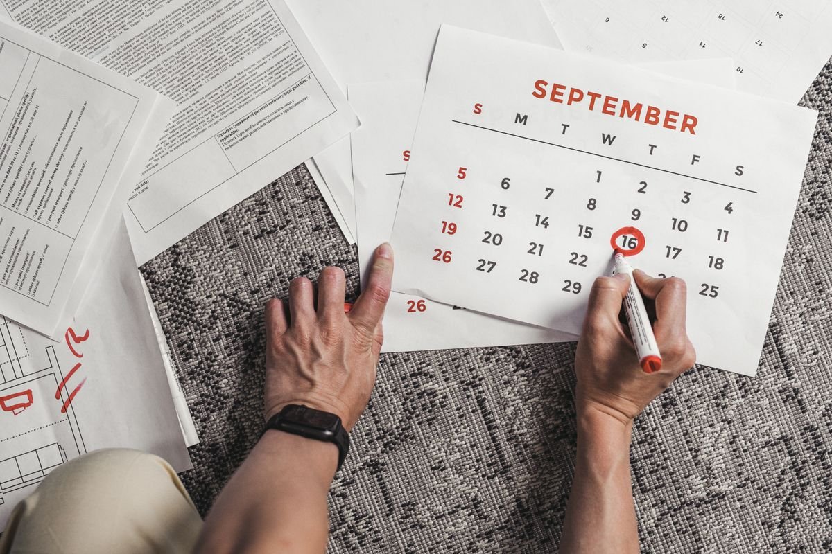 Mains tenant un calendrier avec des dates de septembre encerclées, entouré de