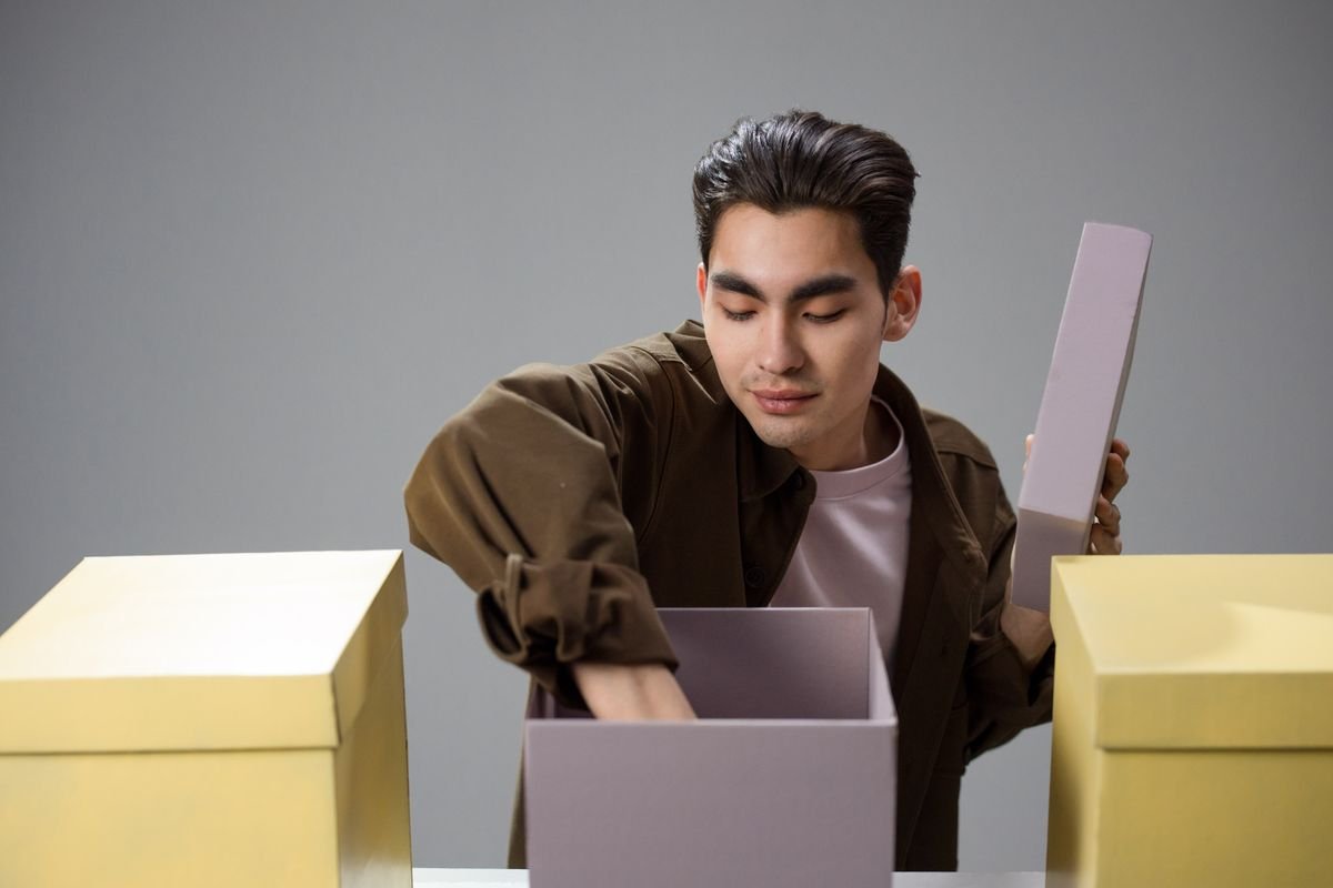 Un jeune homme asiatique explore le contenu des boîtes, suscitant curiosité et