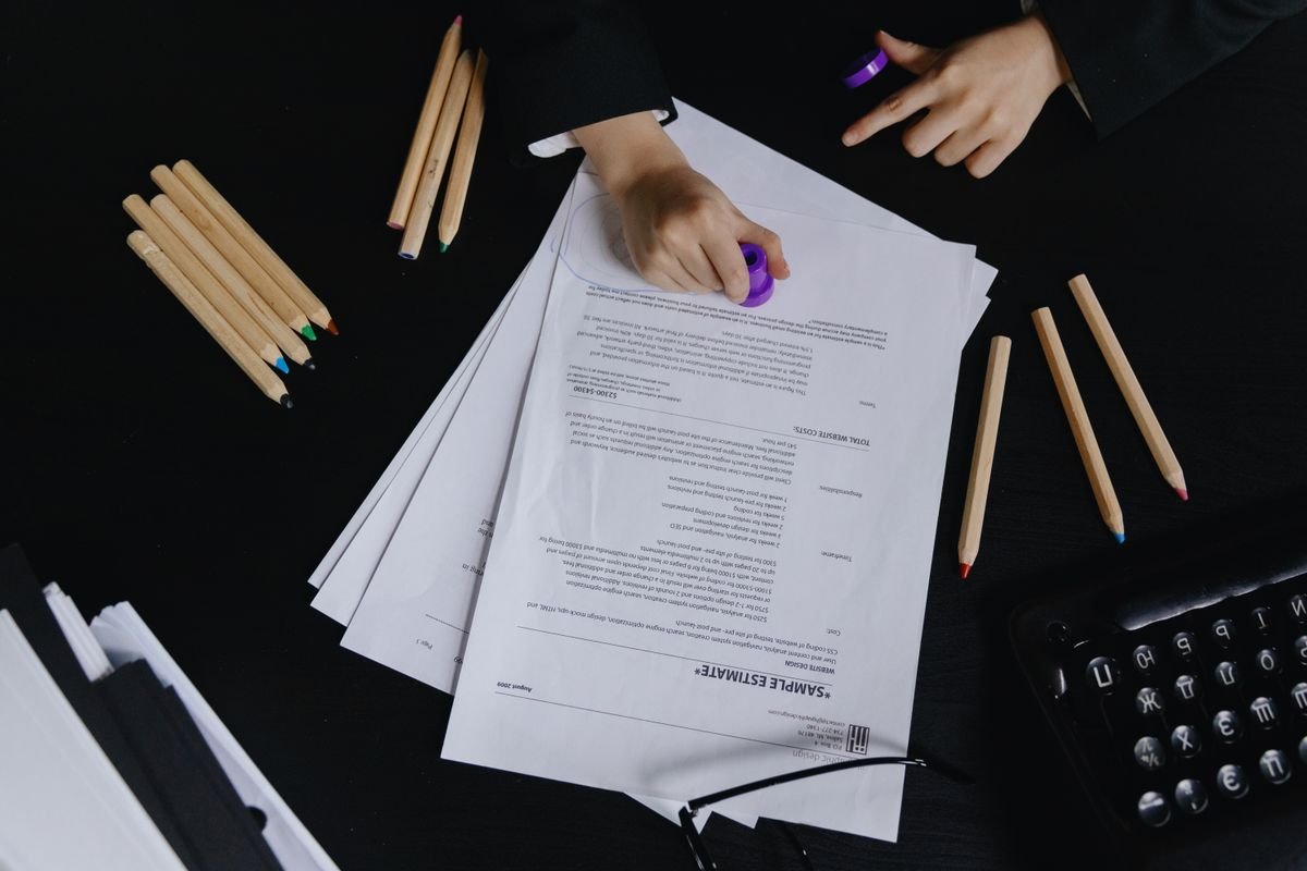 Mains travaillant avec des documents et des crayons de couleur sur un bureau