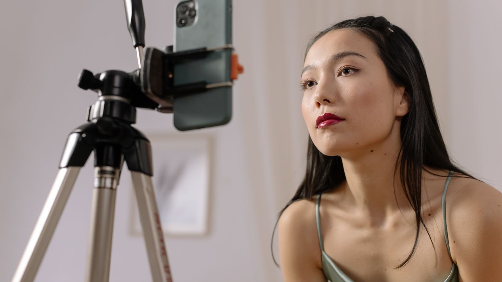 Une femme filmée par un téléphone posé sur un trépied avec un anneau lumineux
