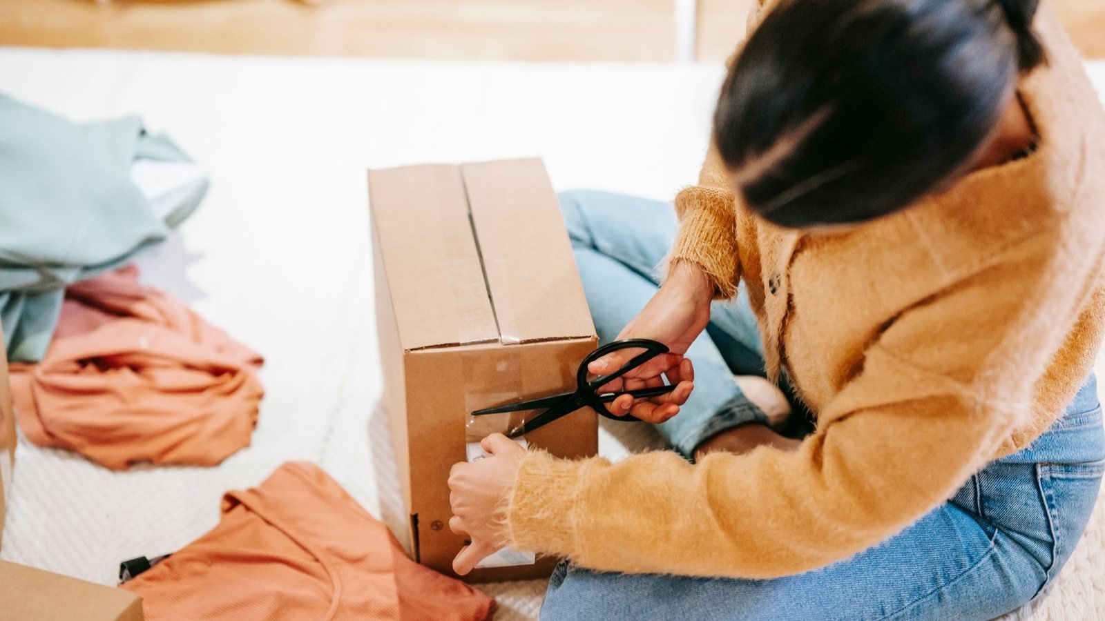 Une femme emballe soigneusement des vetements dans un carton d expedition