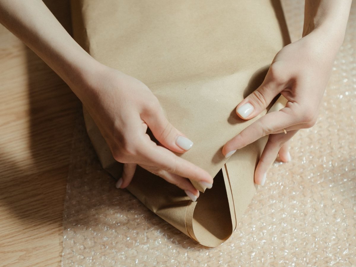 Des mains enveloppent un paquet dans du papier kraft