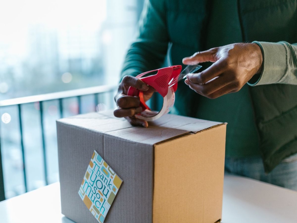 Un homme ferme un carton avec du ruban adhesif