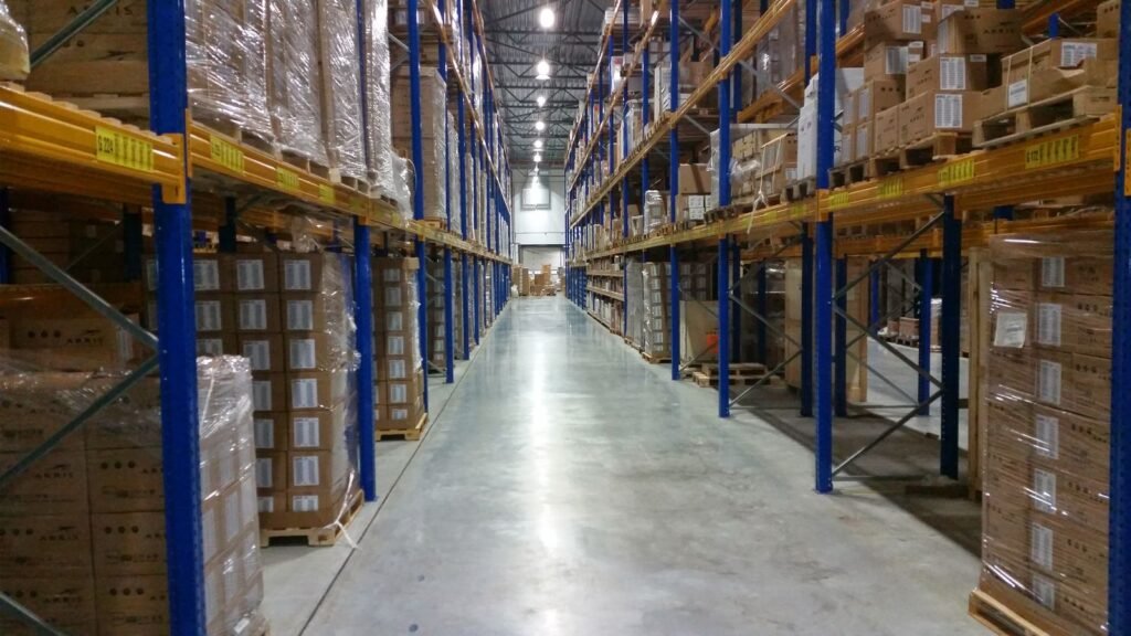 Vendre sur Amazon : les deux choix à faire, et ce qu’ils coûtent Une allée d’entrepôt logistique bordée de rayonnages chargés