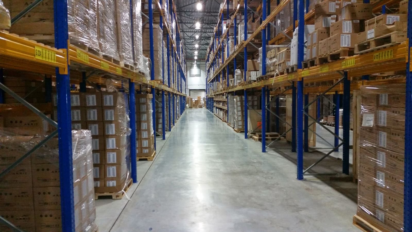 Une allée d’entrepôt logistique bordée de rayonnages chargés